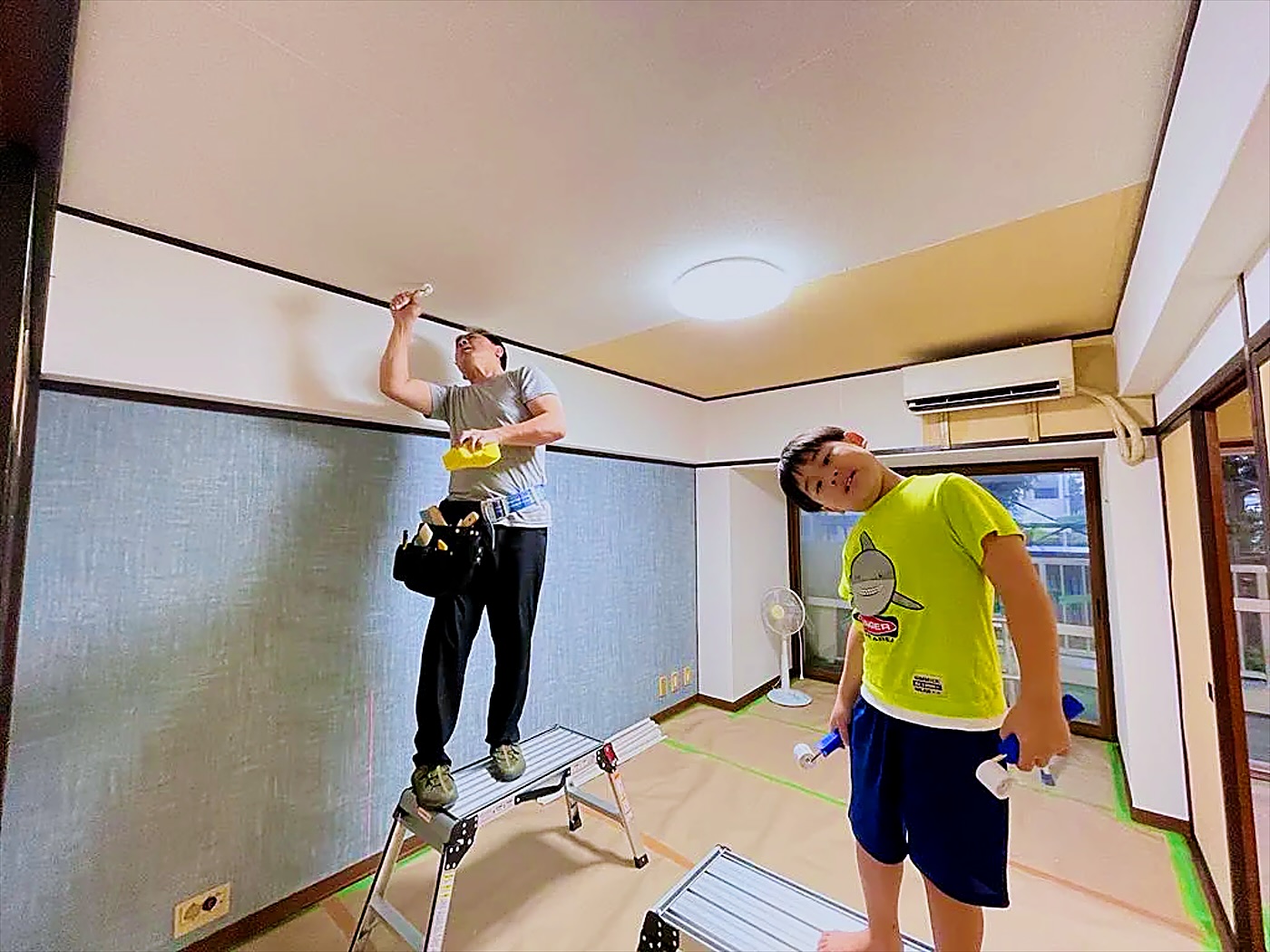 天井の作業をする職人と、お手伝いする子ども